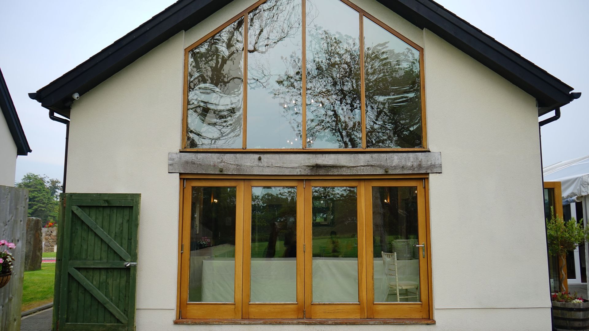Contemporary house facade featuring wooden doors and reflective large glass windows.